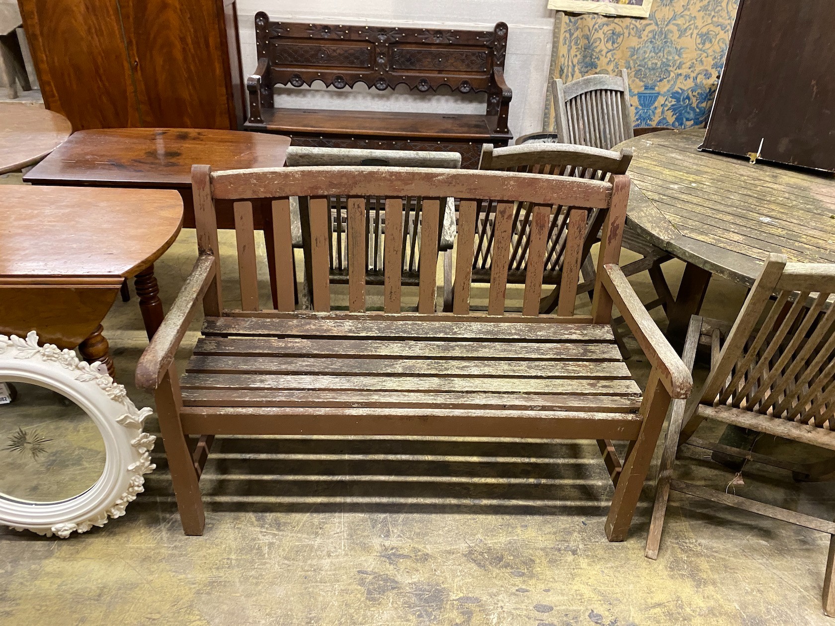 A weathered teak circular garden table, diameter 150cm, height 75cm, a matched set of six folding teak garden elbow chairs, two with arms and a teak garden bench